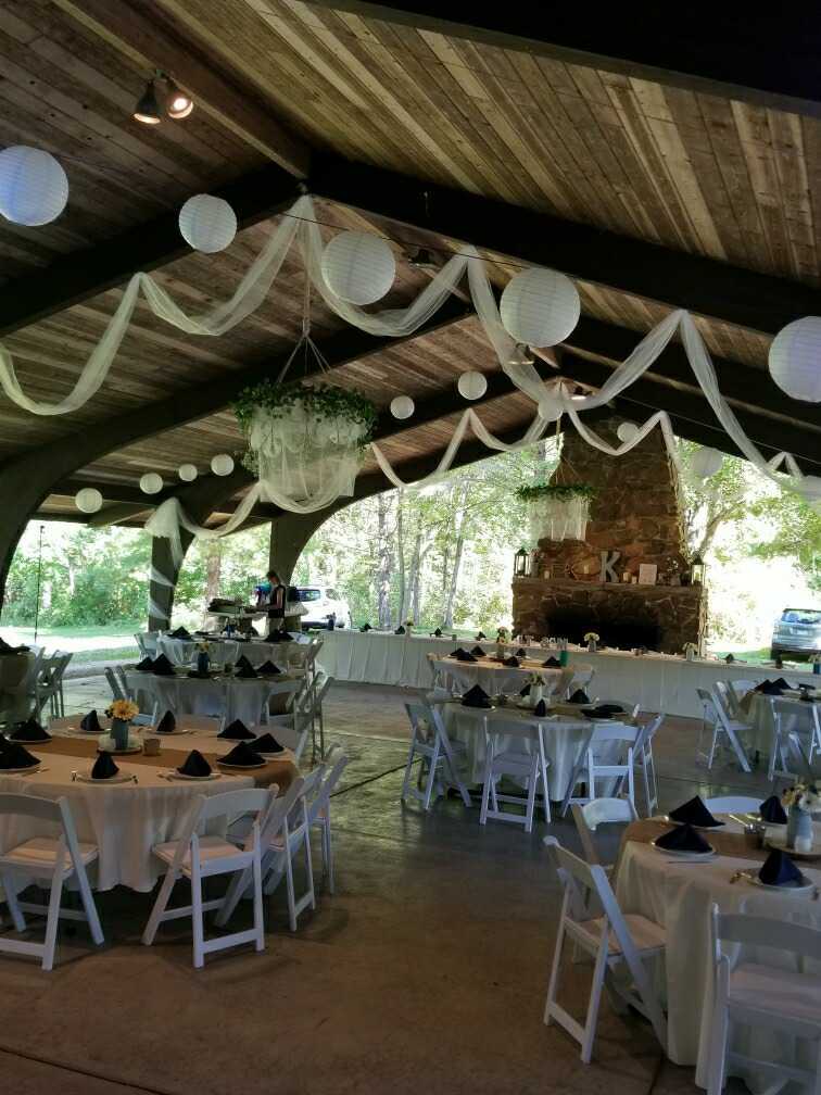 Outdoor pavilion wedding with paper lanterns, draped fabric, and a stone fireplace